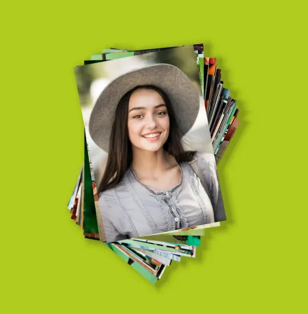 Pila de fotografías impresas sobre fondo verde, con un retrato en la foto superior.