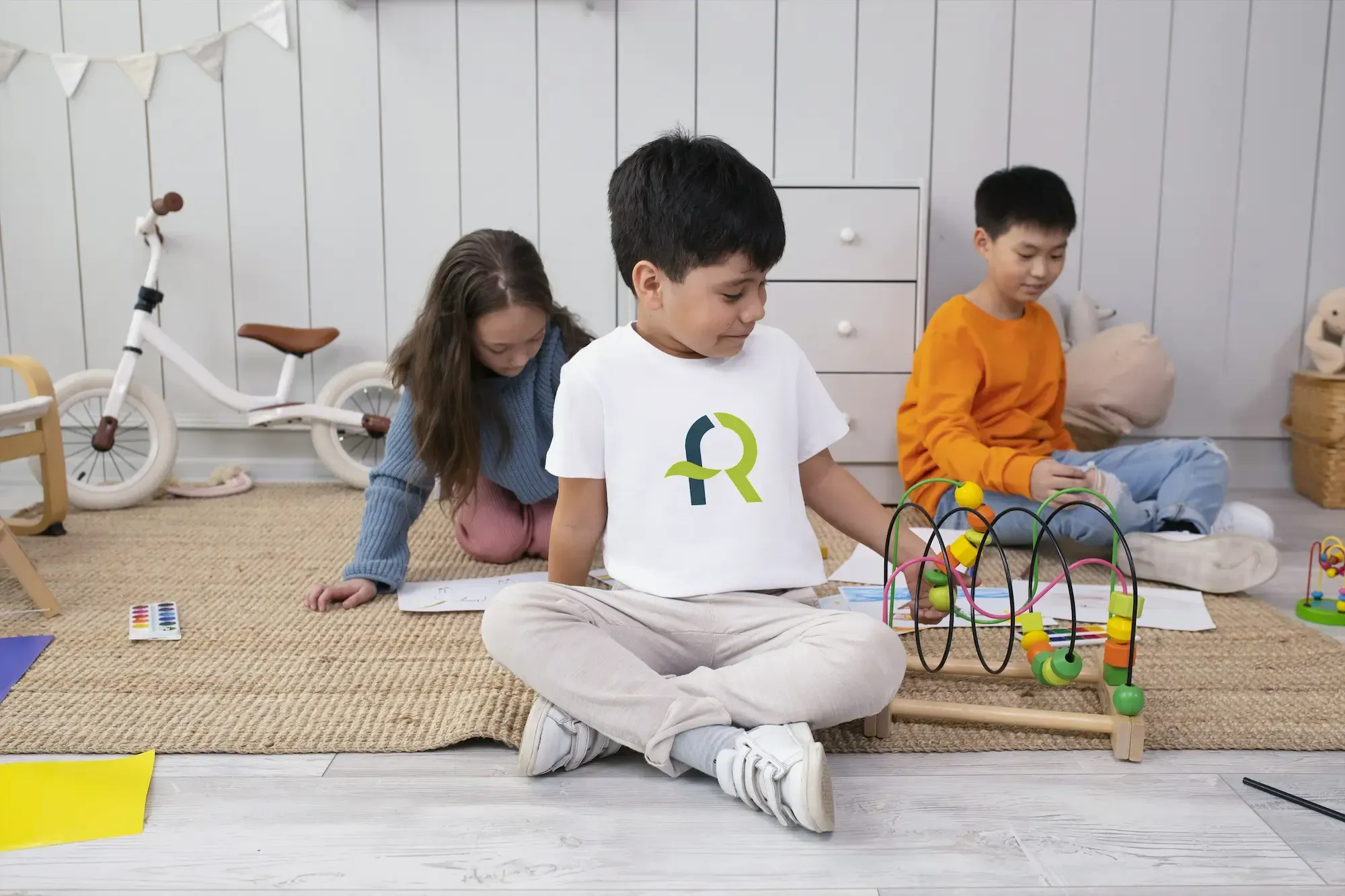 Niño jugando en una sala infantil con una camiseta blanca que muestra el logotipo de AFR Diseño & Impresión.