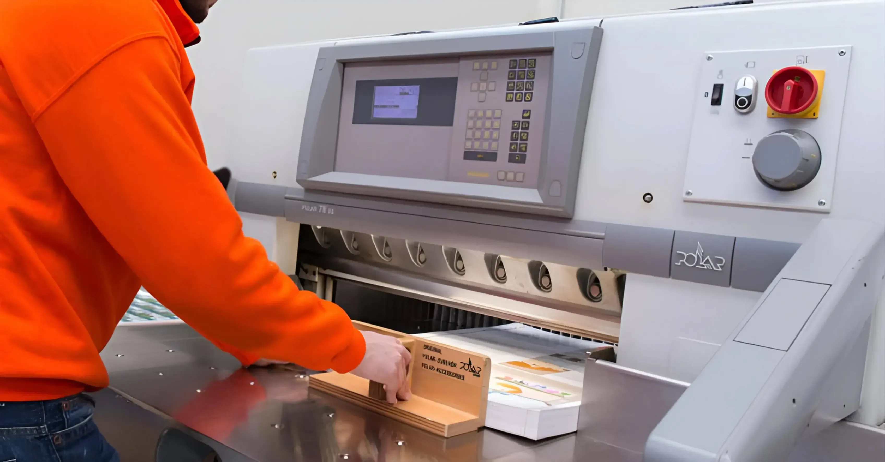 Operario preparando el papel en la máquina para cortarlo.
