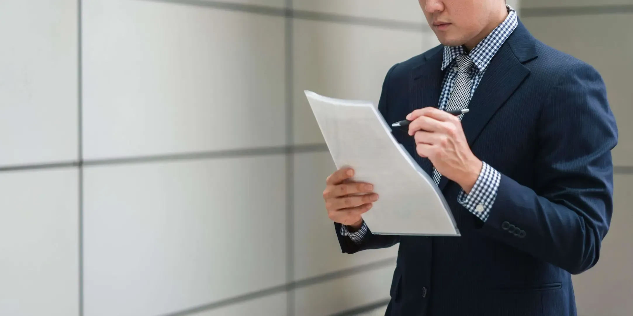 Hombre vestido de traje leyendo unos documentos.