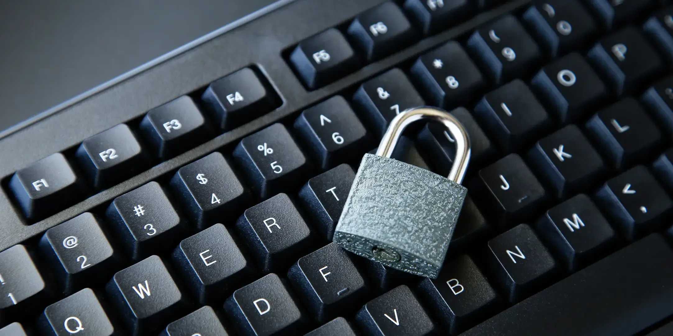 Candado metálico colocado sobre un teclado de ordenador, simbolizando seguridad y protección de datos.